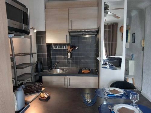 une petite cuisine avec un évier et une table dans l'établissement Pied à terre, séjour idyllique face à la mer classé 2 étoiles, à Sanary-sur-Mer