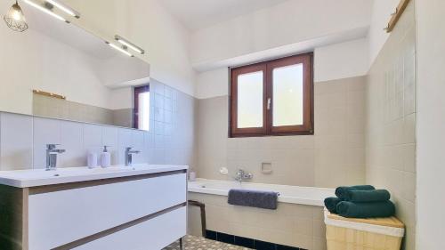 une salle de bain avec un lavabo, une baignoire et un miroir dans l'établissement Les Aubépines - Calme - Parking, à Colmar