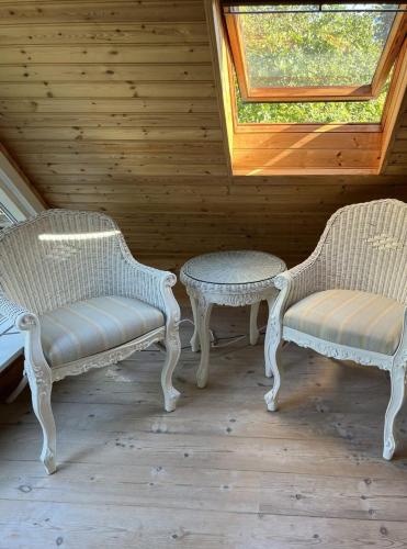 two wicker chairs and a table in a room at Summer House Close To The Sea On North Langeland in Tranekær
