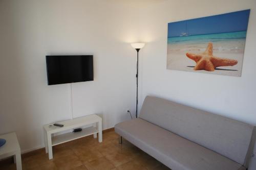 a living room with a couch and a starfish on the wall at Nuvolet Apartaments in Cala en Blanes