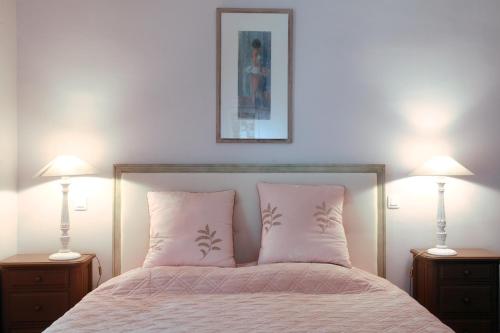 a bedroom with a bed with pink pillows and two lamps at Château de la Prade in Bram