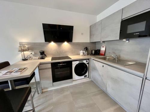 Il comprend une cuisine équipée d'un lave-linge, d'un évier et d'un lave-vaisselle. dans l'établissement Appartement Neuf Climatisé, Terrasse, Parking, Plage à Pied, Cavalaire-sur-Mer - FR-1-226B-106, à Cavalaire-sur-Mer