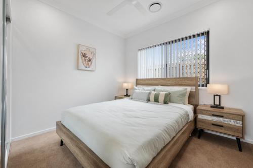 a white bedroom with a large bed and a window at The Crest North Harbour Estate Sleeps 8 in Burpengary East