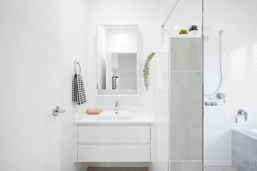 a white bathroom with a sink and a mirror at The Crest North Harbour Estate Sleeps 8 in Burpengary East
