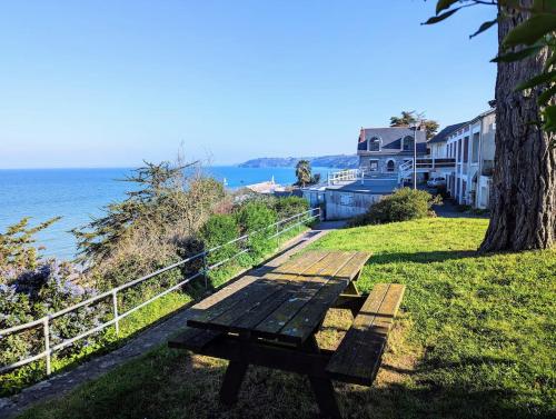 - une table de pique-nique assise sur l'herbe à côté de l'océan dans l'établissement La corniche- vue panoramique sur mer, à Binic