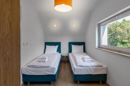 two beds in a small room with a window at Nadmorski Spokój, domki i sauna in Lubiatowo