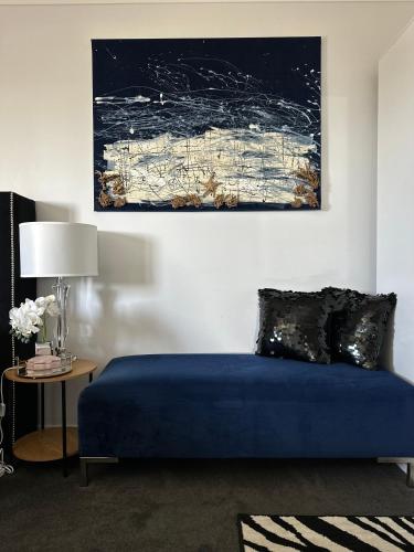 a bedroom with a blue bed and a painting on the wall at Devonport Breeze Escape in Devonport
