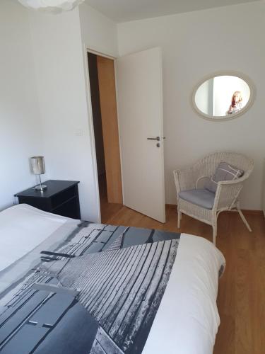 une chambre avec un lit, une chaise et un miroir dans l'établissement Superbe appartement 4 personnes, à Pornichet