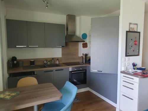 une cuisine avec une table en bois et une chaise bleue dans l'établissement Superbe appartement 4 personnes, à Pornichet