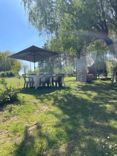 a table and chairs under an umbrella in a yard at Le Mirail in Brugnac