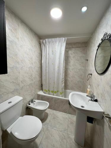 a white bathroom with a toilet and a sink at Atico en Tina Mayor in Unquera