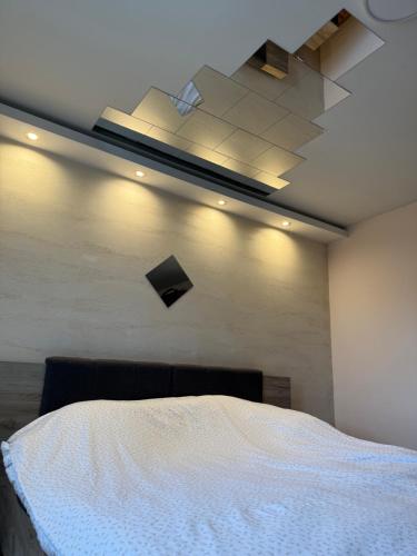 a bedroom with a white bed and a ceiling at Place to Be - Modern Jacuzzi House in Vozdovac in Belgrade