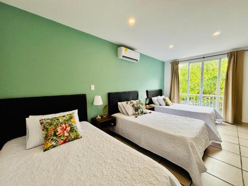 a bedroom with two beds and a green wall at TURULEKA Hostel in Roldanillo