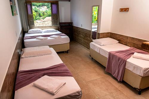 a room with three beds and two windows at Pousada Nativos Lençois in Lençóis