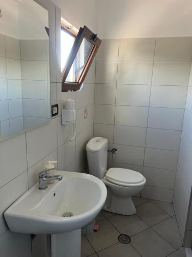 a bathroom with a sink and a toilet and a window at House Pollo in Ksamil
