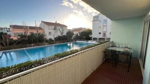 - un balcon avec une table à côté de la piscine dans l'établissement Le Candie T3 Bord de Mer Piscine et Parking, à Canet