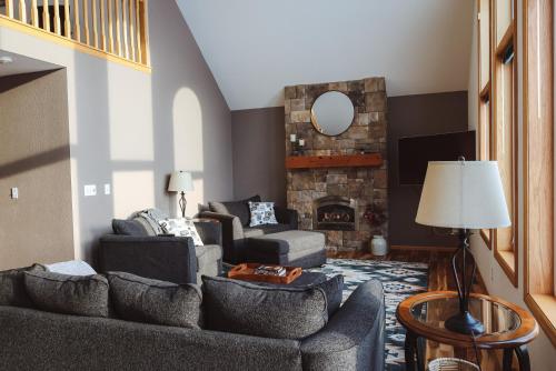 a living room with two couches and a stone fireplace at Love Lake Manor in Nisswa