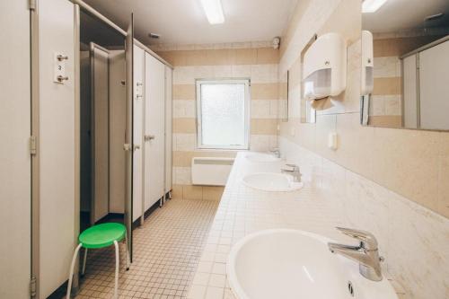 Un baño con dos lavabos y un taburete verde. en Naturcamp Meyersgrund - Campingplatz, en Manebach