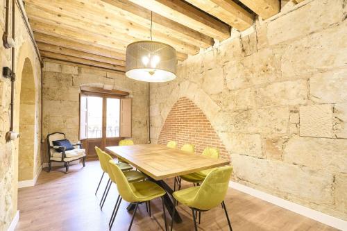 Un comedor con una mesa de madera y sillas verdes. en Apartamentos propia Plaza Mayor collection Luxury, en Salamanca