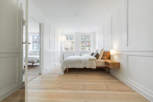 a bedroom with a bed with white walls and wood floors at Luxury Apartment GBT5 in Copenhagen