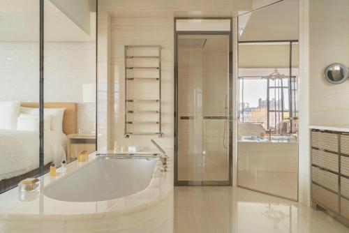a white bathroom with a tub and a bed at Cheval Blanc Paris & Dior Spa Cheval Blanc Paris in Paris
