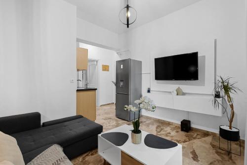 a living room with a couch and a tv on a wall at Andy’s apartments in Georgioupolis