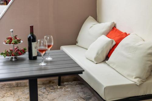 a white couch with two glasses of wine on a table at Andy’s apartments in Georgioupolis