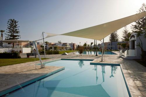 a large swimming pool with a white umbrella over it at Atlantica Marmari Beach in Marmari