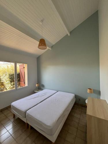 une chambre avec un grand lit blanc dans une pièce dans l'établissement Les Pignes, à Mimizan