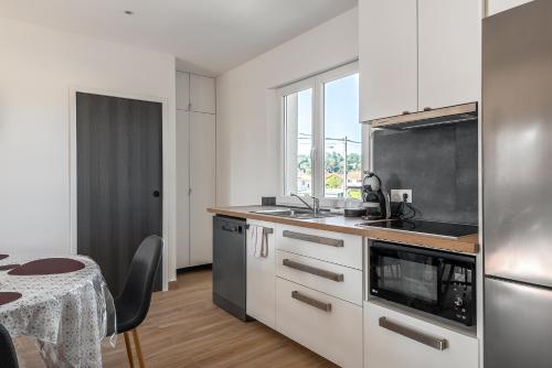 une cuisine avec des armoires blanches, une table et une fenêtre dans l'établissement Apartment 2 bedroomed Lena Montry, à Montry
