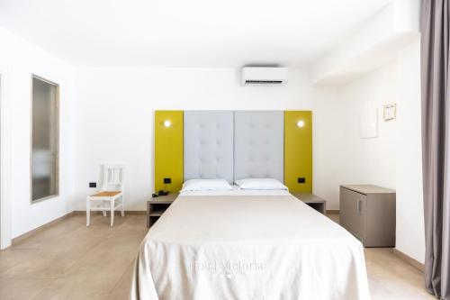 a bedroom with a large white bed with yellow walls at Hotel Victoria in Torre Santa Sabina