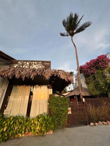 a building with a palm tree and a fence at Espaço Fateixa in Jericoacoara
