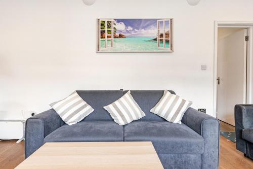 a living room with a blue couch with three pillows at Clapham Common, sleeps 10 2 Bed 2 Bath FREE PARKING for 2 Large Vans or up to 4 Cars Zone 2 Close to Central London and Zone 2 tube station in London