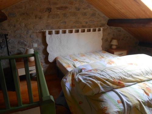1 dormitorio con 1 cama en una pared de piedra en Gite du plô en La Cresse