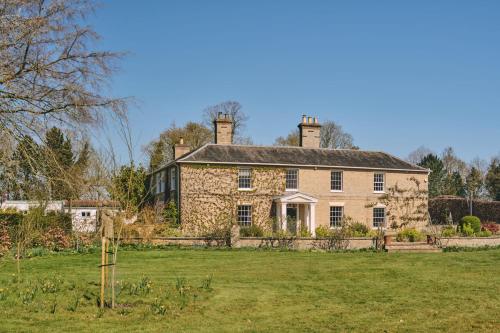 an old stone house with two chimneys on top at Hockham Grange in Hockham