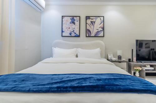a white bedroom with a blue blanket on a bed at استديو فاخر سرير كينج ومطبخ Luxury Studio King Bed in Riyadh