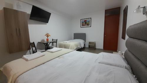 a bedroom with two beds and a flat screen tv at La Rinconada de Churin in Churín