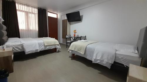 a hotel room with two beds and a television at La Rinconada de Churin in Churín