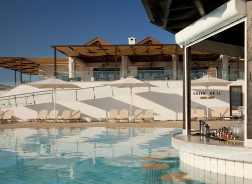 a swimming pool with chairs and umbrellas in a building at Atlantica Marmari Beach in Marmari