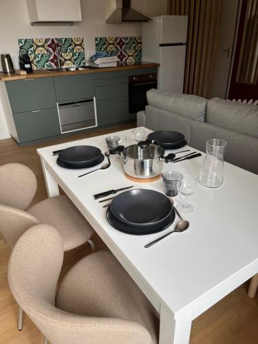 - une table blanche avec des assiettes et des bols dans la cuisine dans l'établissement Entre Montagnes et lacs Gites, à Les Piards