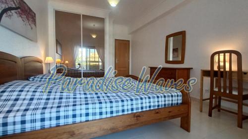 Schlafzimmer mit einem Bett mit einer blauen und weißen Bettdecke in der Unterkunft Magnifique appartement 500m de la plage avec piscine in Porches