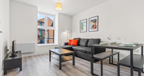 a living room with a black couch and a table at 1BR Apartment with Sofa Bed I Prime Town Centre Location I Gold St D-Lux, Modern Amenities, Walk to Train, Bus Stations, Shops & Cafés I Leisure and Business Stays Welcome MULTIPLE UNITS AVAILABLE in Northampton