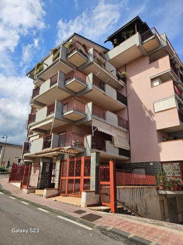 a tall pink building with balconies on a street at Casa ATENA in Santa Teresa di Riva