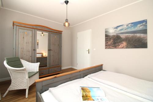 a bedroom with a bed and a chair and a cabinet at Ostseeresidenz Appartements Wischuer Fewo 26 in Wischuer