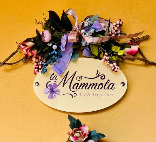 a sign with a bunch of flowers on a yellow wall at La Mammola Bed&Breakfast in Fabriano