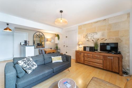 un salon avec un canapé bleu et une télévision dans l'établissement Appart 2 chambres sur Quais des Chartrons, à Bordeaux