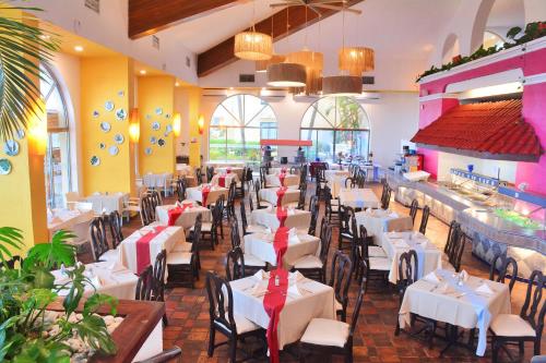 a dining room with white tables and chairs at All Ritmo Cancun Resort & Water Park in Cancún