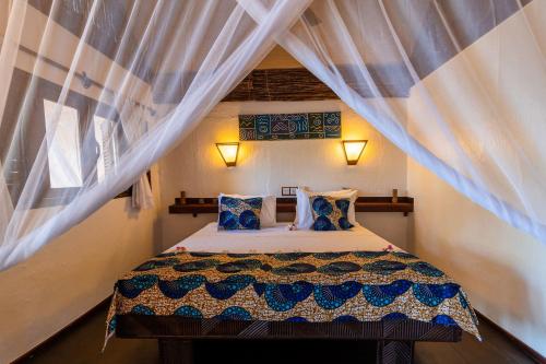 a bedroom with a bed in a room with curtains at Pole Pole Bungalows in Utende