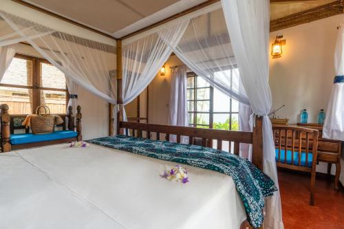 a bedroom with a canopy bed with flowers on it at Pole Pole Bungalows in Utende