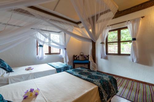 a bedroom with two beds and two windows at Pole Pole Bungalows in Utende
